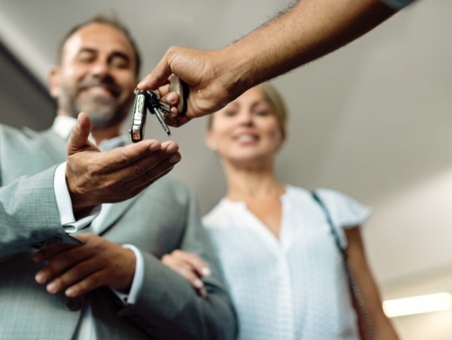 Close-up of mechanic giving car keys to a couple in auto repair shop.